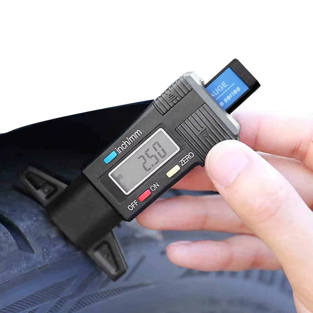 Digital tyre tread depth gauge measuring a car tyre