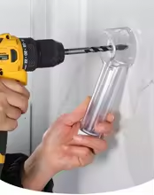 Transparent drill dust collector attachment in use on a wall